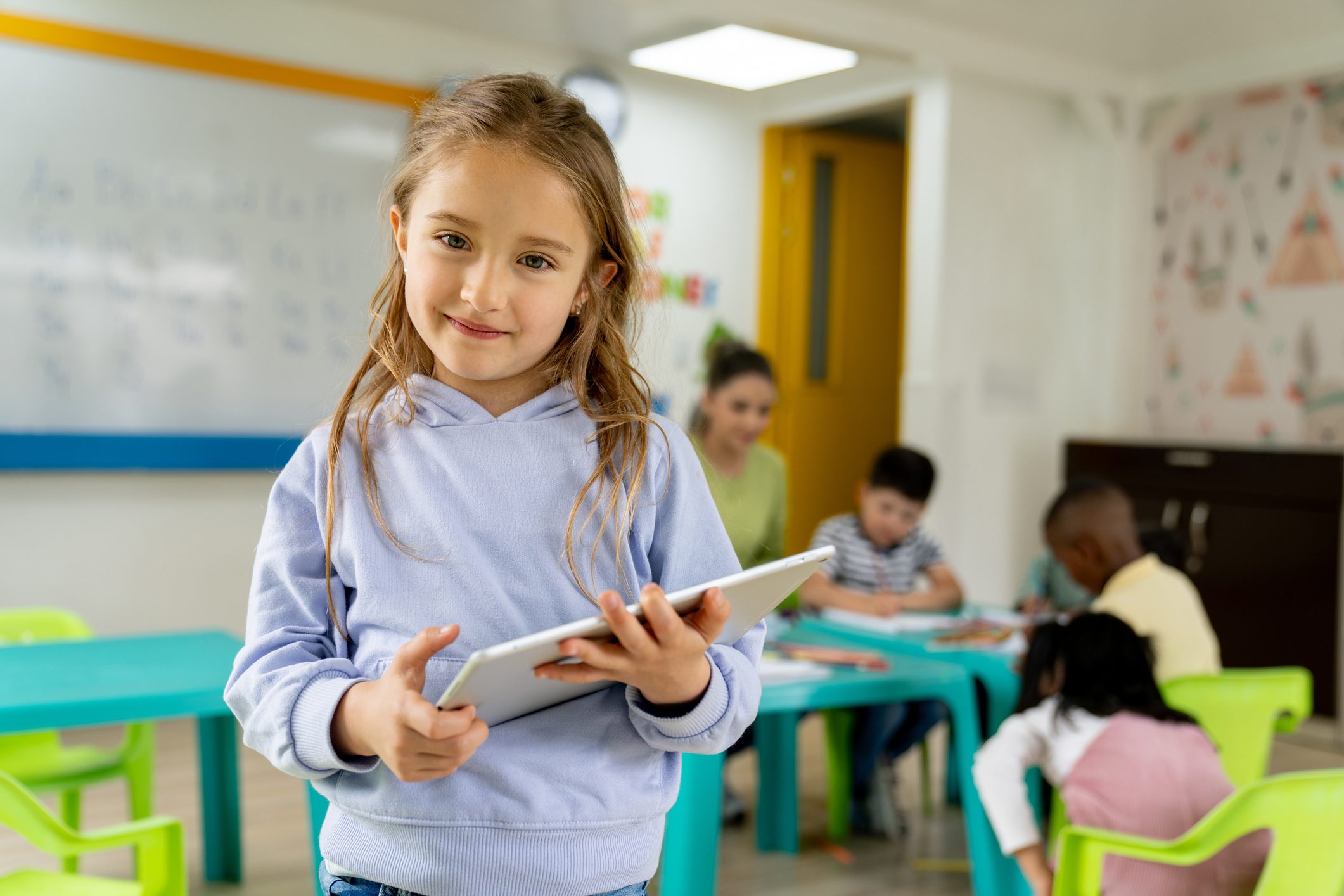 Young girl holding tablet in classroom